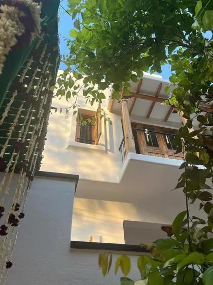 A glimpse of my first project in Mysore, showing a traditional balcony with wooden shutters, seen through lush foliage.
