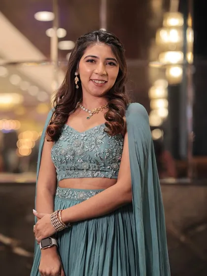 A lovely look for a pre-wedding event. The soft waves and clean makeup create a fresh and youthful appearance that perfectly matches her light blue pleated lehenga.