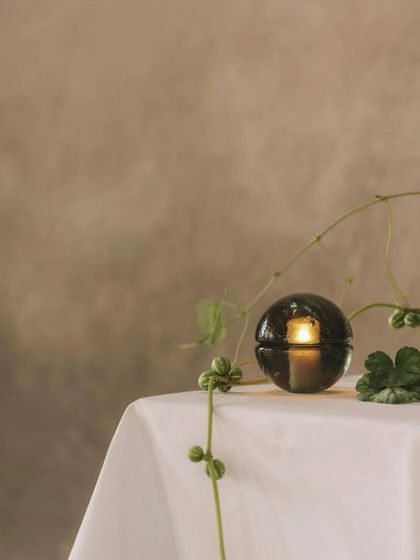 A single smoked grey 14p on a white tablecloth, its simple elegance making it a beautiful object even when unlit.