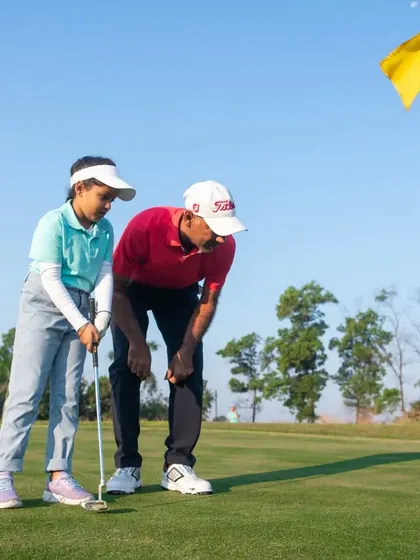 One-on-one attention is crucial for our junior golfers. Here, a coach helps a young student with her putting alignment, making learning both effective and enjoyable.