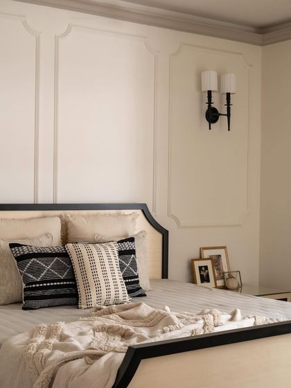The layered bedding with its mix of textures and patterns adds warmth and personality to this elegant black and cream bedroom.