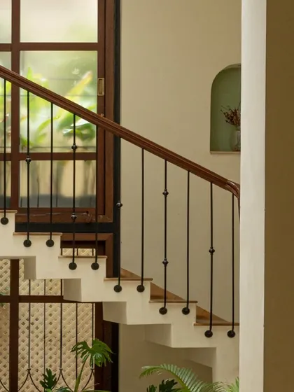 The elegant curve of the staircase at Casa 503. The design combines solid steps with open railings and large windows, ensuring the space feels bright and connected to the lush greenery outside.