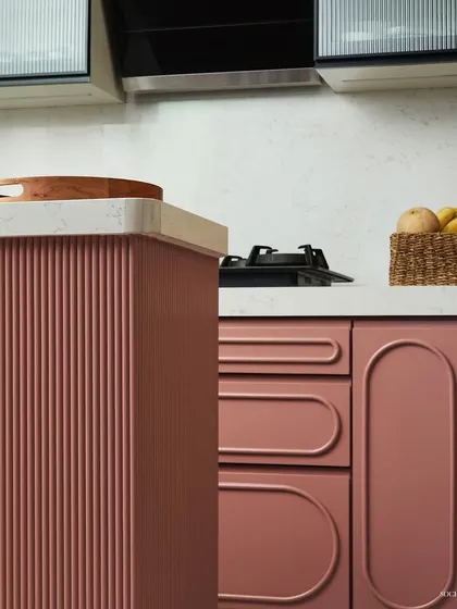 A close-up of the kitchen cabinetry, highlighting the combination of fluted panels and smooth, curved drawer fronts. These details add a layer of sophistication and tactile interest to the design.