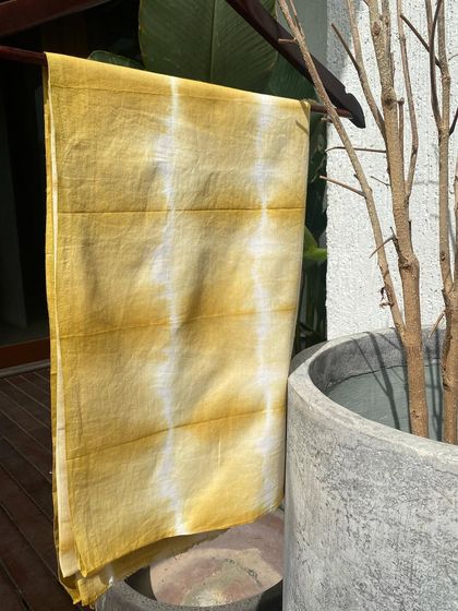 The onion skin-dyed fabric hanging to dry. The natural light brings out the warm, golden tones of the dye.