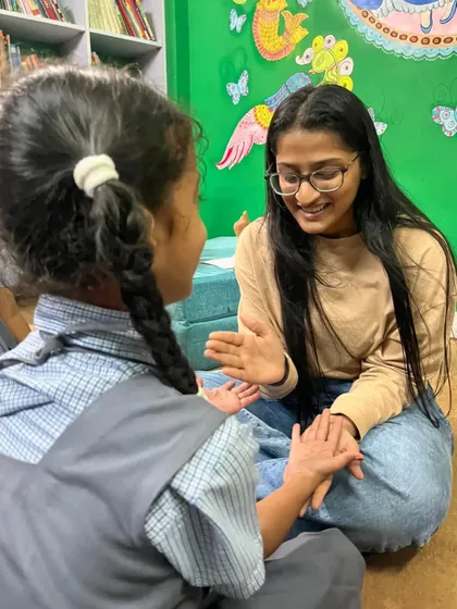 A volunteer shares a quiet moment with a young girl, their hands playing a game. These simple interactions build trust and connection, which are just as important as the stories themselves.