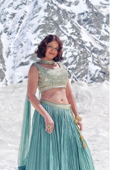 A model posing in our light green lehenga against a snowy mountain. Our outfits are perfect for adventurous destination photoshoots.