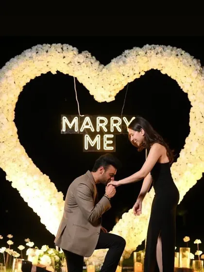 The perfect shot to announce your engagement. We design our proposal setups to be incredibly photogenic, ensuring you have beautiful memories to share, like this moment in front of a "Marry Me" sign.