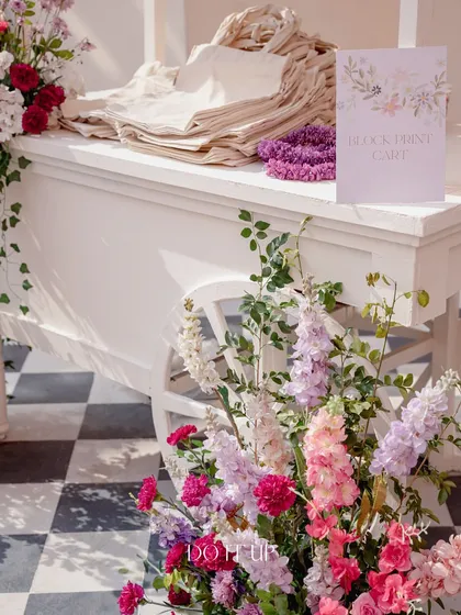 A charming white cart set up as a block printing station for guests. This interactive element, adorned with fresh flowers, allowed guests to engage with a local craft during the welcome lunch.
