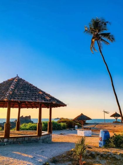 A peaceful evening at Malpe Beach, with its beach shacks and palm trees.