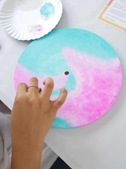 A close-up of a participant creating a soft, blended effect on a resin clock with pastel colors.