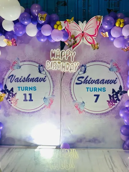 A close-up of the joint butterfly birthday backdrop, featuring a neon "Happy Birthday" sign that adds a modern touch to the classic theme.