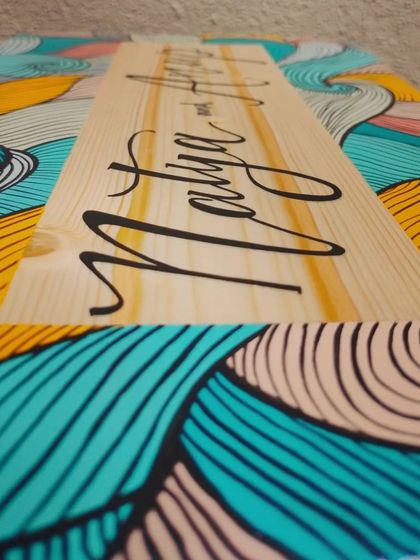 A detailed angle of our boho-style name plaque. The intricate line work is done entirely with a fine paintbrush, showing the care and precision that goes into each piece.