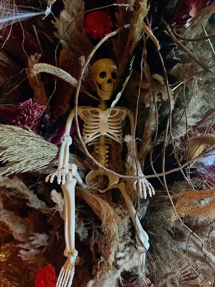 A skeleton nestled within a large, dried floral arrangement, adding a spooky touch to the decor.