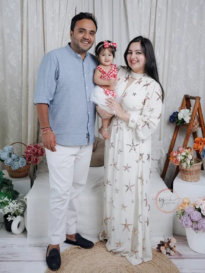 A bright and happy family portrait in a boho-chic studio setting. The light colors and relaxed poses create a warm and inviting image of this beautiful family of three.