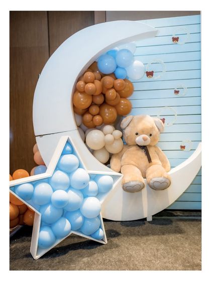 Another view of the moon and star photo booth, emphasizing the soft color palette of the balloons and the adorable placement of the teddy bear.
