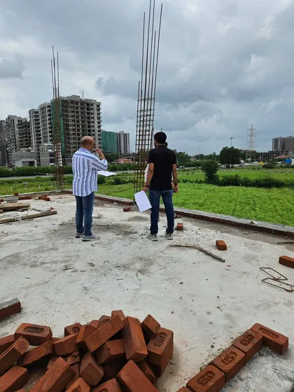 Surveying a new construction site against the backdrop of the city. I assess the land's slope, energy, and surrounding environment before planning the Vastu layout.