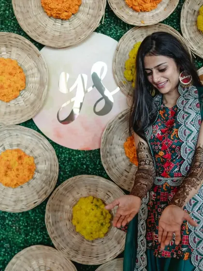 A personalized backdrop for a mehendi, using woven baskets, marigolds, and the couple's initials for a rustic-chic touch.