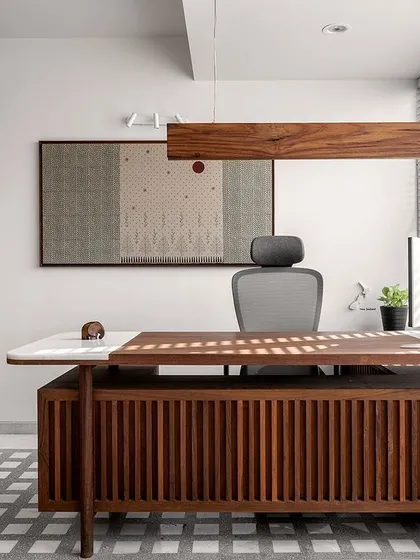 We designed the director's cabin in the 'On The Grid' office to be a space of calm focus. The custom-fluted wood desk with a marble top, paired with a linear hanging light, creates a clean, minimalist aesthetic, while louvered blinds allow for controlled natural light, enhancing the productive atmosphere.
