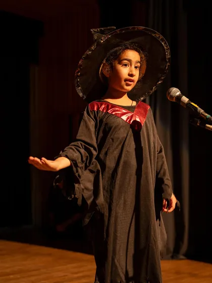 A young witch mid-speech. This shows a strong, confident stance and clear vocal delivery.