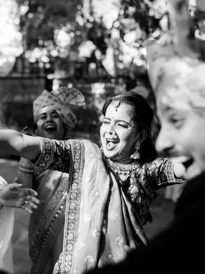 A black and white photo that captures the pure, uninhibited joy of dancing in a baraat. The bride's friend is having the time of her life.