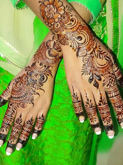 The same beautiful Indo-Arabic design, showing how the patterns on both hands create a stunning pair. The white nail polish makes the henna color pop.