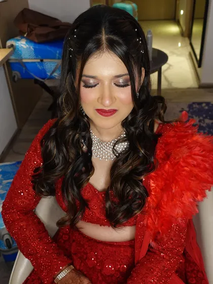 My bride Amileen's Sangeet makeover. She is wearing a stunning red sequin lehenga with a feather boa, and her makeup is pure glam.