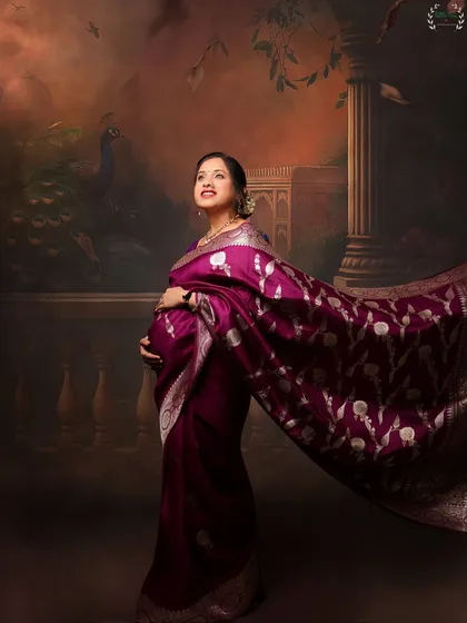 A majestic shot of a mother-to-be in a flowing saree against a painted backdrop, creating a royal, artistic feel.