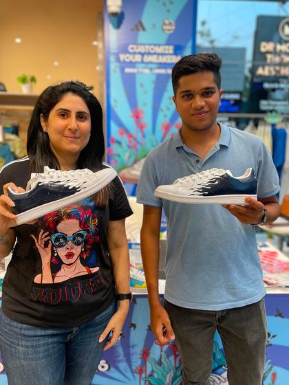 A couple showing off their matching custom sneakers with a cool white flame design. We can create complementary designs for pairs or groups.