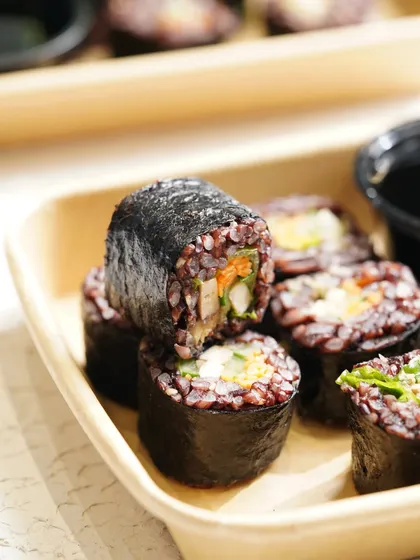 A close-up shot of black rice sushi rolls, focusing on the texture and fresh ingredients inside.