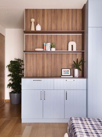 As avid collectors, my clients needed a large bookshelf. I designed this unit with a mix of open shelves and closed cabinets, using a powder blue and wood finish to match the room's decor. The edges are curved for safety and accessibility.