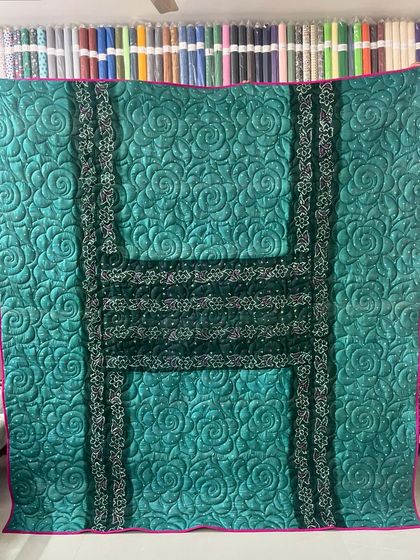 A full view of a reversible memory quilt made from sarees, featuring a bold 'H' design created with the saree borders.