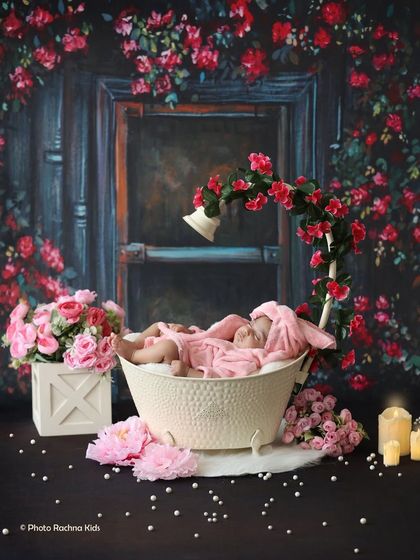 A luxurious bath-time theme for a newborn, dressed in a tiny pink robe and sleeping in a miniature tub surrounded by roses and candles.