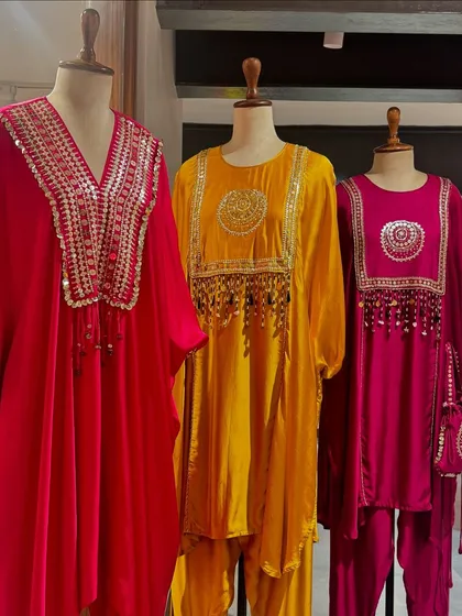 A trio of festive tunics by Prahnaaya in bright red, yellow, and pink, featuring ornate mirror work and tassel details.