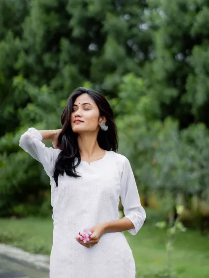 A serene, eyes-closed moment. This portrait focuses on the feeling of peace and elegance, enhanced by the simple beauty of the white kurta.