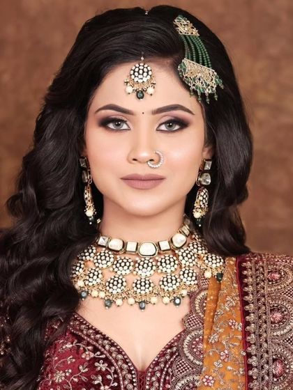 A model wearing a white and gold Kundan choker set with a matching maang tikka and a green passa. This combination offers a unique twist on the traditional bridal look.