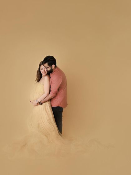 A wide shot that feels both grand and intimate. The couple is wrapped in a bubble of love, a beautiful fine art portrait from their glamourous maternity session.