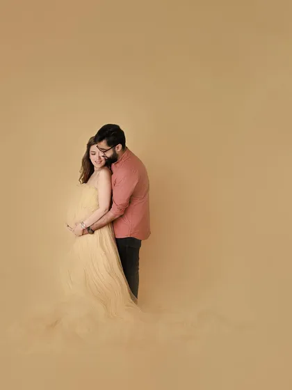 A wide shot that feels both grand and intimate. The couple is wrapped in a bubble of love, a beautiful fine art portrait from their glamourous maternity session.
