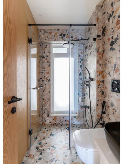 This daughter's bathroom is made with vibrant terrazzo tiles and dramatic black bathroom fittings. The design is playful yet sophisticated, with a black basin and a sleek, modern toilet.