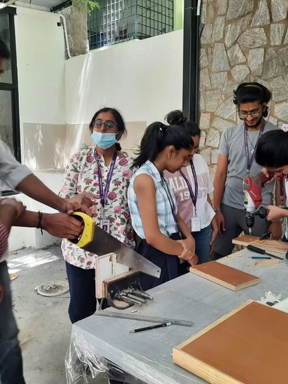 A group of architecture students learning how to use a hand saw. These foundational skills are essential for any designer.