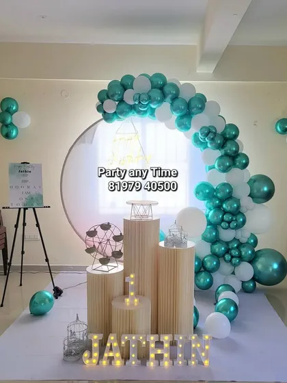 A wide shot of the elegant 1st birthday decoration, showing the full balloon arch and prop arrangement in the party hall.