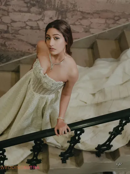 A dramatic and fashionable shot of the bride on a grand staircase. The angle and her pose highlight the stunning details and trail of her gown.