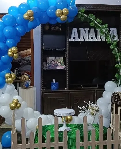 A blue and white balloon arch integrated into a home's living room furniture for a personalized celebration.