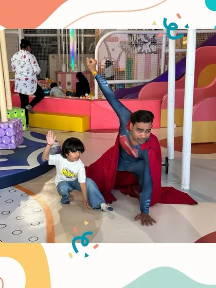 Up, up, and away. A young boy strikes a superhero pose with our Superman mascot.