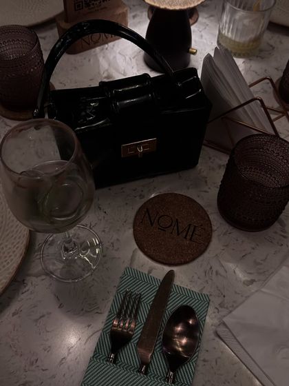 A flat-lay style shot of a chic black box bag on a dinner table, showing how a bag can be a centerpiece.