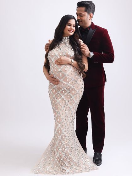 An elegant pose showcasing the couple's connection and the stunning detail of the maternity gown. A perfect shot for a high-fashion maternity album.