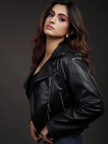 A model in a black leather jacket and jeans, captured in a classic three-quarter portrait against a grey studio background. This is a staple look for a versatile model portfolio.