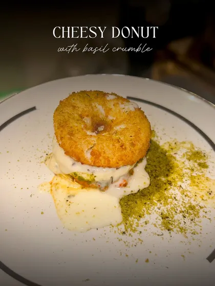 A plated view of my savory Cheesy Donut with basil crumble. This image highlights the golden brown crust of the donut and the rich, creamy sauce, promising a unique and delicious appetizer.