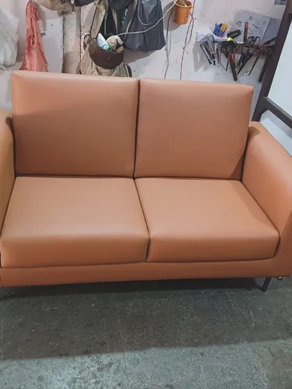 A compact and stylish two-seater sofa in a tan leatherette, made for a client's office. Its clean lines and metal legs make it a professional and comfortable seating option.