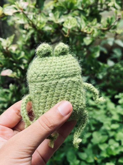 A hand-held shot of the frog AirPods case, showing its size and adorable little face.