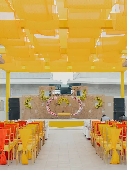 The seating arrangement for a Haldi ceremony, with a bright yellow canopy and chairs decorated in shades of yellow and orange.
